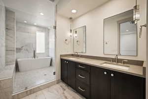 Full bath featuring double vanity, recessed lighting, a freestanding bath, light marble finish floors, and a stall shower
