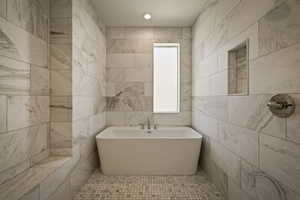 Full bathroom featuring a freestanding bath and tile walls