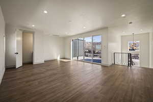 Unfurnished living room featuring hanging lights, dark wood-style flooring, and a textured ceiling