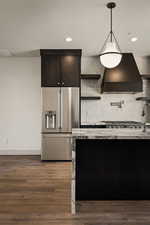 Kitchen with open shelves, high end fridge, dark wood-type flooring, tasteful backsplash, and light stone countertops