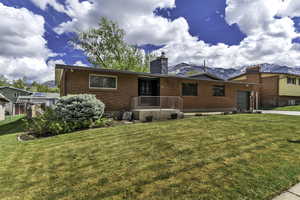 Rear view of property with brick siding, a garage, a lawn, and a mountain view
