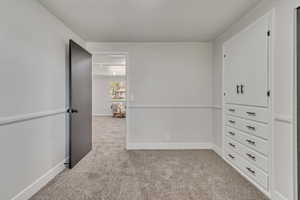 Unfurnished bedroom with light carpet and baseboards