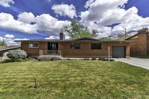 Single story home featuring brick siding, an attached garage, a front lawn, and concrete driveway