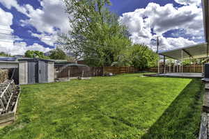 Fenced backyard featuring a storage unit and a patio area