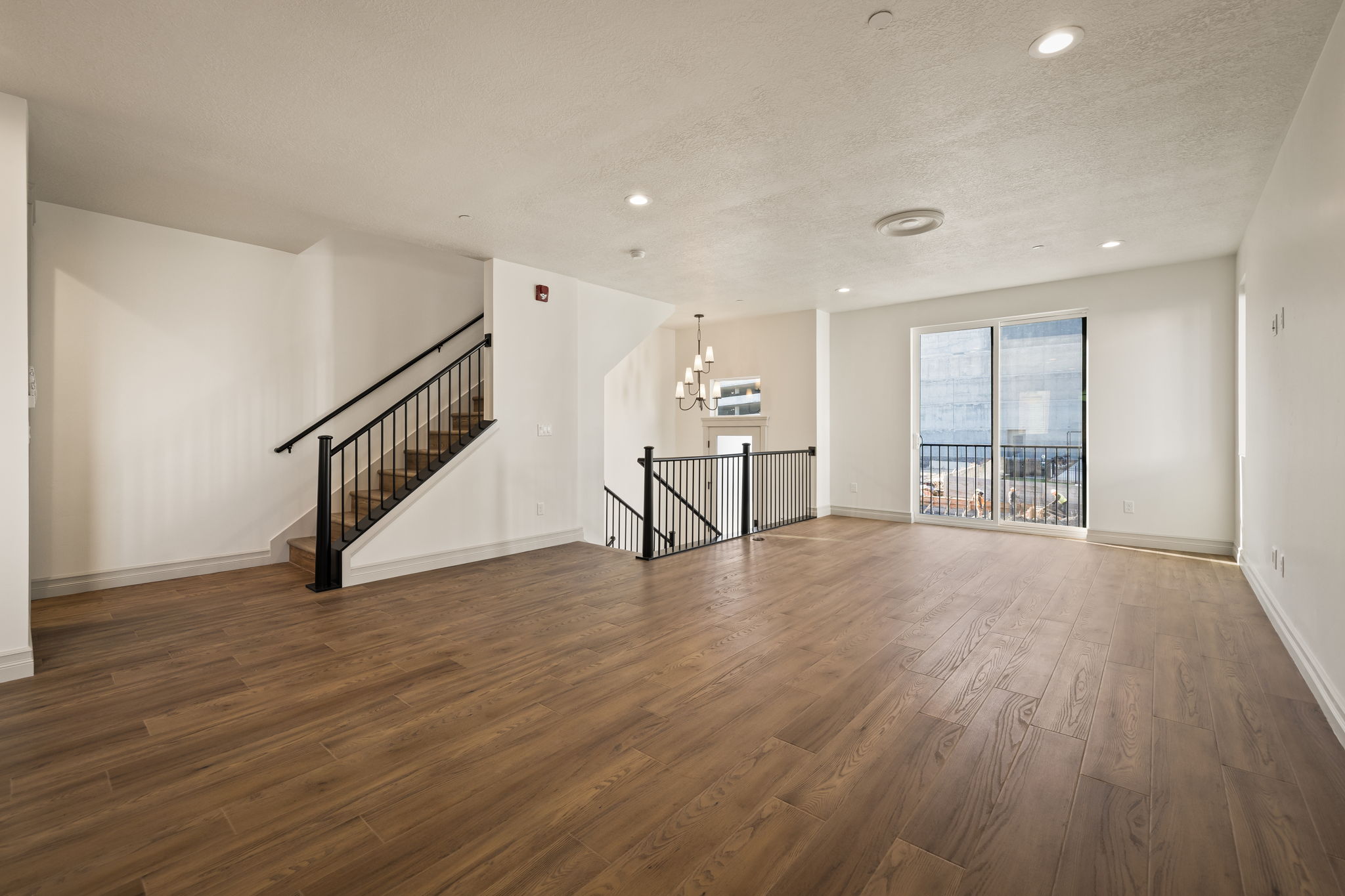 Unfurnished living room featuring dark wood-style flooring, a textured ceiling, and a chandelier