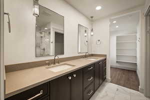 Bathroom with double vanity, light marble finish flooring, a tile shower, and recessed lighting