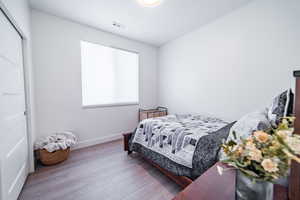Bedroom with wood finished floors and a closet