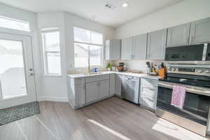 Kitchen with stainless steel appliances, gray cabinetry, light wood-style floors, and recessed lighting
