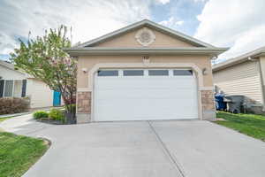 View of front facade featuring stone siding, stucco siding, concrete driveway, and a garage