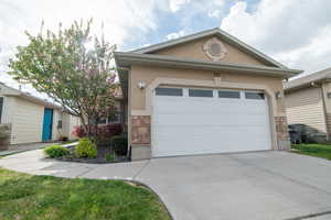 View of front of house with stone siding, concrete driveway, a garage, and stucco siding