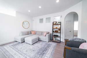Living area featuring arched walkways, wood finished floors, and recessed lighting