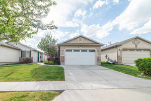 Ranch-style home featuring driveway, stucco siding, a front lawn, and an attached garage