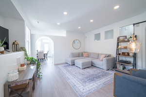 Living area featuring arched walkways, light wood-style floors, and recessed lighting