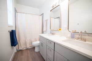 Bathroom featuring double vanity, dark wood-type flooring, and shower / bath combination with curtain