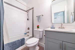 Bathroom with vanity, shower / bath combination with curtain, and dark wood-style floors