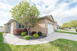 View of property exterior featuring an attached garage, driveway, a yard, stone siding, and stucco siding