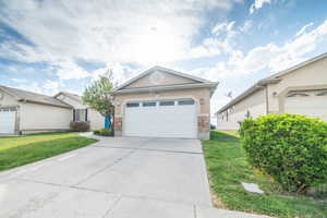 Ranch-style house featuring concrete driveway, stone siding, a front lawn, a garage, and stucco siding