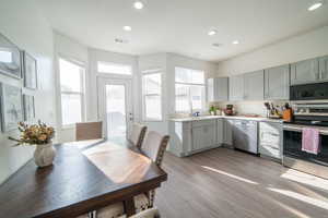 Kitchen with light countertops, stainless steel appliances, light wood finished floors, gray cabinets, and recessed lighting