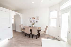 Dining space with recessed lighting, light wood finished floors, and arched walkways