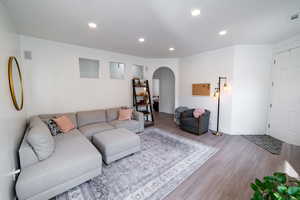 Living room featuring arched walkways, wood finished floors, and recessed lighting