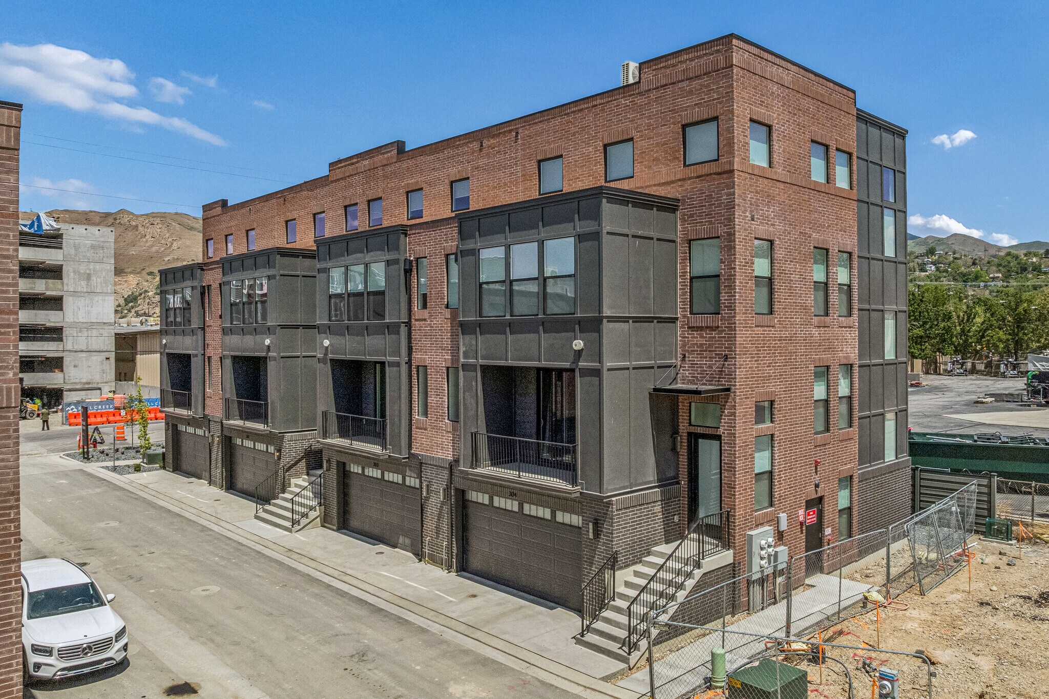 Contemporary townhome architecture featuring a brick facade, integrated garage access, and private balconies
