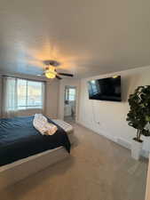 Carpeted bedroom with multiple windows, a textured ceiling, a ceiling fan, and connected bathroom