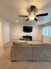 Living room featuring ceiling fan, light colored carpet, and a textured ceiling
