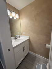 Half bathroom featuring vanity, dark wood-style flooring, and a textured wall