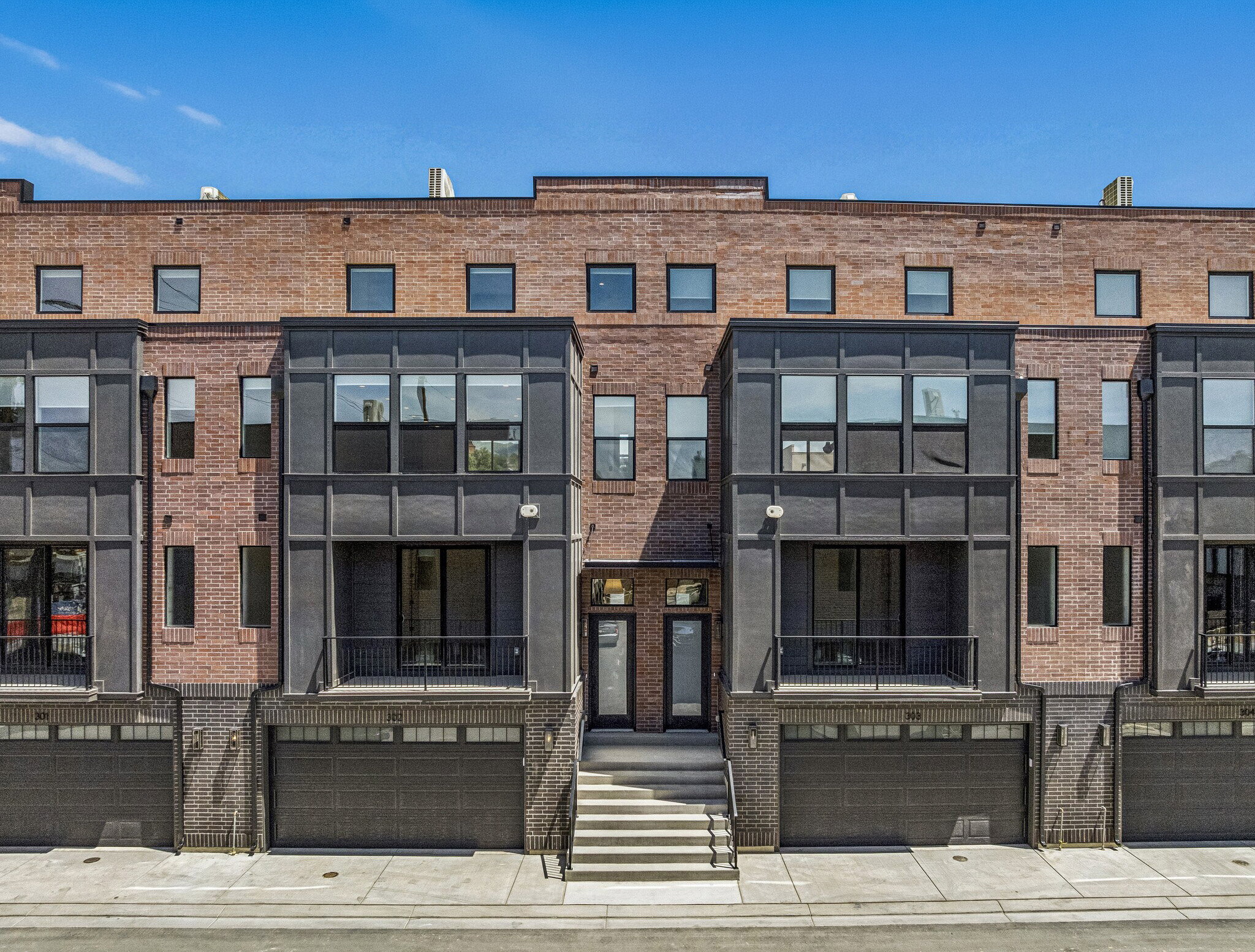 Contemporary townhome exterior featuring a brick facade with dark gray architectural accents