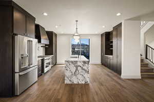 Kitchen featuring premium appliances, light stone counters, and dark wood finish cabinetry