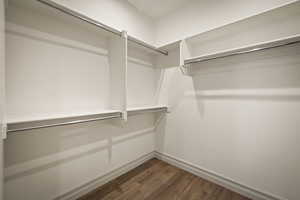 Walk in closet with dark wood-style flooring