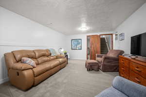 Living room with carpet floors, a textured ceiling, and wainscoting