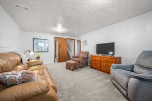 Carpeted living room with a textured ceiling and stairs