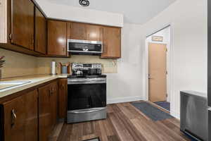 Kitchen featuring stainless steel appliances, light countertops, and dark wood-style floors