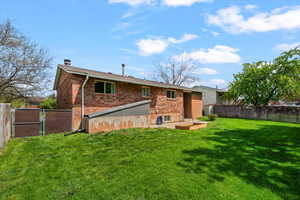 Rear view of property with a fenced backyard, a gate, a chimney, brick siding, and a deck