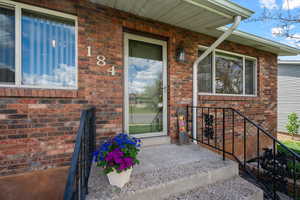 Doorway to property featuring brick siding and a porch