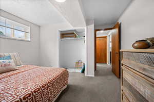 Bedroom with light colored carpet, a closet, and a textured ceiling