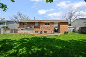 Rear view of property featuring brick siding, a fenced backyard, and a patio