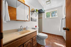 Bathroom featuring vanity, a textured ceiling, dark tile patterned floors, and a shower