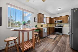 Kitchen with stainless steel appliances, light countertops, a ceiling fan, dark wood-style floors, and wood finish cabinets