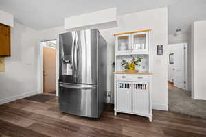 Kitchen featuring glass insert cabinets, stainless steel fridge with ice dispenser, a textured ceiling, white cabinetry, and dark wood finished floors