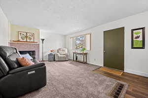 Carpeted living area featuring a fireplace and a textured ceiling