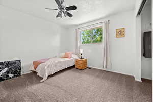 Carpeted bedroom with ceiling fan and a textured ceiling