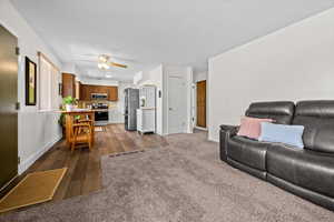 Living area with dark wood-style floors, ceiling fan, dark colored carpet, and a textured ceiling