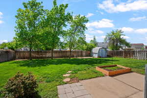 Fenced backyard featuring a storage shed, a patio area, and a vegetable garden