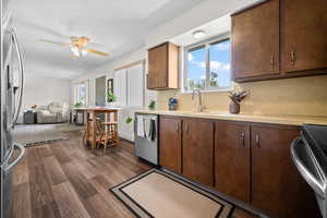 Kitchen featuring stainless steel appliances, light countertops, dark wood finished floors, ceiling fan, and open floor plan