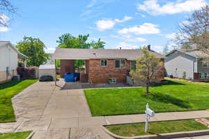 Ranch-style home with brick siding, a shingled roof, driveway, and an outbuilding