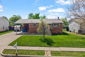 Single story home featuring an outdoor structure, brick siding, an attached carport, and driveway