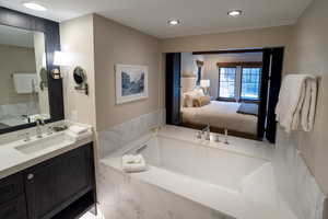 Bathroom featuring a bath, vanity, and connected bathroom