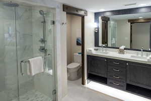 Full bathroom featuring double vanity and a stall shower